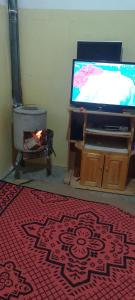 a living room with a television and a red rug at Auberge le calme restaurante in Bou Drarar