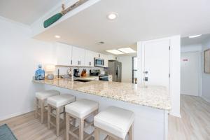 a kitchen with white cabinets and a counter with stools at Wind Drift 310S condo in Orange Beach