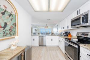 a kitchen with white cabinets and a large painting on the wall at Wind Drift 310S condo in Orange Beach