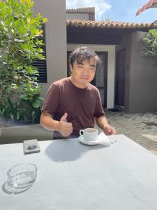 a man sitting at a table with a cup of coffee at The Urban Escape in Matara