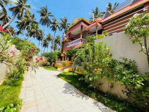 a house with palm trees and a walkway at selvis casa in Pondicherry