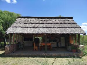 a small hut with a thatched roof with a table at Cabañas Entre Verde in Los Hornillos