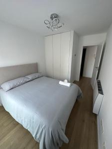 a white bedroom with a large bed and a chandelier at 60m2 Cozy Apartament in Valencia