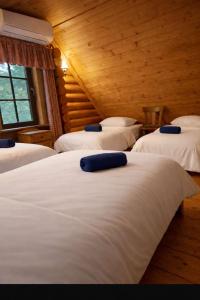 a room with four beds with white sheets and blue pillows at Jugland-Private Riverside Retreat with Sauna & Hot Tub in Bajāri