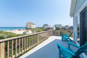 a porch with two blue chairs and the beach at Desi's Delight - S Nags Head MP 20.5, Ocean View, 30 Yards to Beach, Cargo Lift, YR Flex Stays in Nags Head