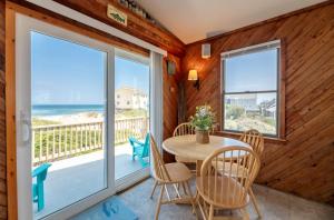 a dining room with a table and chairs and a balcony at Desi's Delight - S Nags Head MP 20.5, Ocean View, 30 Yards to Beach, Cargo Lift, YR Flex Stays in Nags Head