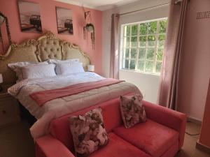 a bedroom with a large bed and a red couch at Silver Gates BnB in Mbabane
