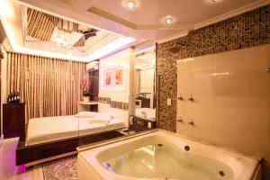 a large bathroom with a tub and a bed at Golden Motel Diária suítes amplas, conforto premium e total privacidade in Passo Fundo