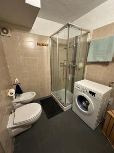 a bathroom with a shower and a toilet and a washing machine at Il nido delle cime in Capriana