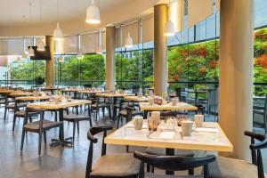 a restaurant with tables and chairs and large windows at NH Collection Guadalajara Providencia in Guadalajara