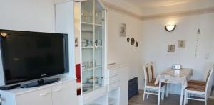 a living room with a television and a dining room table at Ferienwohnung De Kiewitt 207 in Dorum-Neufeld