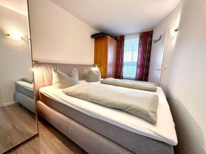 a bedroom with a bed and a mirror at Ferienwohnung De Kiewitt 207 in Dorum-Neufeld +3 photos