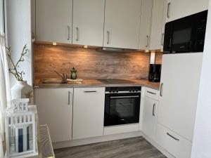 a kitchen with white cabinets and a stove and a sink at Ferienwohnung De Dwarslöper in Dorum-Neufeld