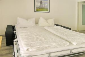 a bed with white sheets and pillows on it at Ferienwohnung De Dwarslöper in Dorum-Neufeld