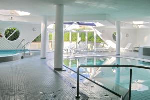a swimming pool with tables and chairs in a building at Ferienwohnung De Dwarslöper in Dorum-Neufeld +1 photo