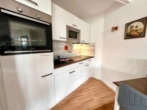 a kitchen with white cabinets and a sink and a microwave at Ferienwohnung De Dörsch in Dorum-Neufeld