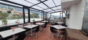 a restaurant with tables and chairs and large windows at Tin House Quito in Quito
