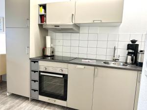 a kitchen with white cabinets and a sink at Ferienwohnung De Priel in Dorum-Neufeld