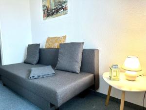 a grey couch with pillows sitting next to a table at Ferienwohnung De Priel in Dorum-Neufeld +3 photos