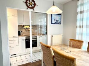 a kitchen with white cabinets and a wooden table at Ferienwohnung de Drift in Dorum-Neufeld