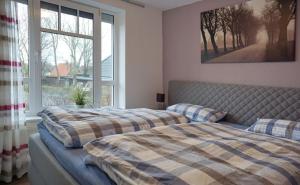 a bedroom with two beds and a large window at Ferienwohnung de Drift in Dorum-Neufeld