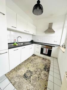a kitchen with white cabinets and a rug on the floor at Bright temporary apartment in Schkeuditz in Schkeuditz