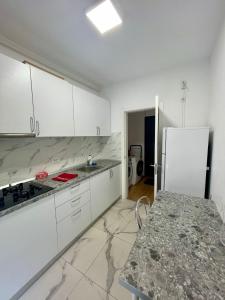 a kitchen with white cabinets and a marble counter top at Waterfall Studio in Bucharest