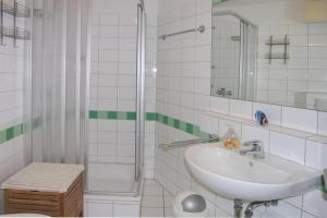a white bathroom with a sink and a shower at Ferienwohnung De Keef in Dorum-Neufeld +2 photos