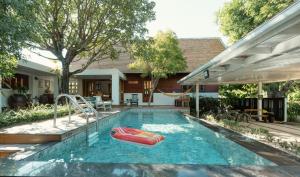 a swimming pool with a raft in a backyard at Whisper Oasis - Award-Winning Private Jacuzzi Pool Villa - 3BR, Daily Service in Chiang Mai