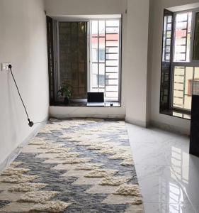 a room with a rug on the floor and a window at The Travellers Nest in Siliguri