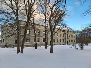 a large brick building with trees in the snow at Tammiku apartment in Kunda