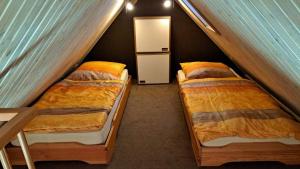 two beds in a small room with a small refrigerator at LHMW19A12-FeWo-Seglerfruend-II in Westerbergen