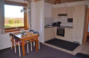 a kitchen with a wooden table and a table and chairs at LHMW19A03-FeWo-Seglerfruend-III in Westerbergen