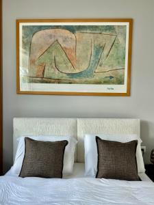 a picture hanging above a bed with two pillows at גיל נכסים #2 in Caesarea +29 photos