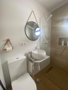 a bathroom with a white toilet and a mirror at Los Llanos del Campo in Grazalema +47 photos