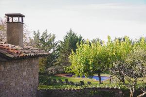 a garden with chairs and a pool in the background at Cal Terri Rural in Perafita