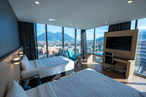 ein Hotelzimmer mit zwei Betten und einem Flachbildfernseher in der Unterkunft Hotel Kavia Monterrey in Monterrey