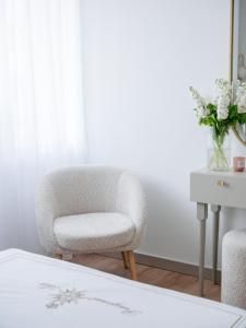 a white chair sitting in a room with a table at Willa Ada Pokoje & Apartamenty in Karwia