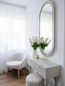 a dressing table with a chair and a mirror at Willa Ada Pokoje & Apartamenty in Karwia