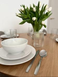a wooden table with a bowl and a vase of white flowers at Willa Ada Pokoje & Apartamenty in Karwia +85 photos