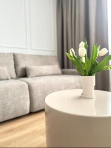 a white coffee table with a vase of flowers on it at Willa Ada Pokoje & Apartamenty in Karwia