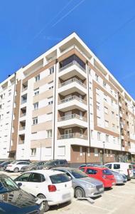 a large building with cars parked in a parking lot at Apartman Matija in Pale