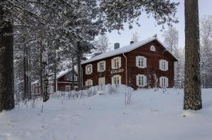 a large wooden house in the snow with trees at Lantlivlodge i Österjörn - Midgård in Jörn