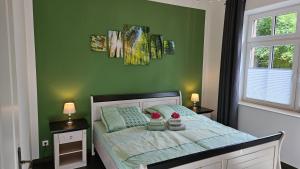 a bedroom with a bed with green walls and two windows at Herrenhaus Darbein in Dargun