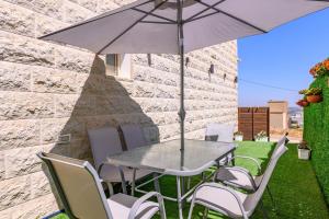 a table and chairs with an umbrella on a lawn at Villa Alba in Majdal Shams