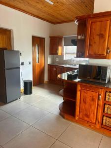 a kitchen with wooden cabinets and a stainless steel refrigerator at Rosies on Robin - Pool, Braai & Mountain Views in Rustenburg