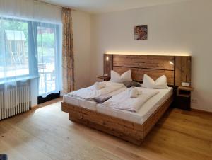 a bedroom with a large bed with a wooden headboard at Bayerischer Wald, FVI Hotel und Restaurant in Neukirchen +5 photos