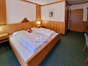 a bedroom with a large bed with white sheets at Bayerischer Wald, FVI Hotel und Restaurant in Neukirchen