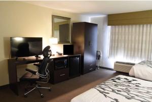a hotel room with a bed and a desk with a chair at Sky Harbor Airport Inn in Phoenix