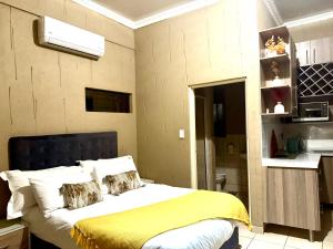a bedroom with a bed with a yellow blanket at Tshiamo Estate in Kuruman